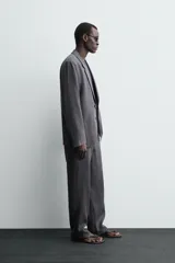 Pantalón de traje regular fit confeccionado en tejido de lino, con cierre frontal de cremallera y botón, bolsillos laterales y bolsillos traseros de vivo.