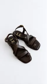 Sandalias de cuero color marrón con diseño de tiras cruzadas en el empeine, sujetador para el dedo y tira ajustable con hebilla en el talón.