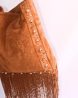Cartera tipo shoulder bag de cuero gamuzado color suela, con diseño de flecos en la base y detalle de tachas metálicas en los laterales. Cuenta con correa regulable y forro interior.