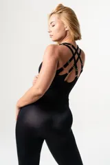 Mono deportivo negro de lycra, con breteles elásticos regulables cruzados en la espalda y detalle de aros metálicos.