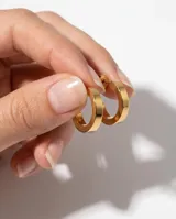 Caravanas tipo argolla de acero con acabado dorado y diseño de perfil plano.