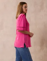 Remera de algodón color fucsia, marca Ruby Rd. con cuello redondo con escote en V y mangas cortas amplias con aplique de crochet en el borde.