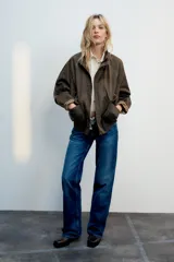 Chaqueta encerada color marrón con efecto lavado, cuello subido y manga larga. Cuenta con bolsillos frontales de plastrón y cierre de cremallera oculto por solapa con botones a presión. Los puños reversibles dejan ver un forro interior con estampado a cuadros.