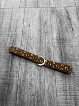 Cinto marrón de gamuza con hebilla metálica plateada y ojalillos metálicos.