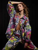 Pantalón de gabardina con estampado floral multicolor, corte carrot fit, tiro medio, estilo carpintero, con botón de metal personalizado, pieza carpintera y parche trasero personalizado.