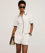 Short Marfinno de viscolino color blanco, con cintura elástica, bolsillos simulados en la parte trasera y ribetes en contraste negros.