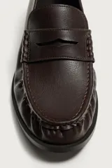 Mocasín de vestir para hombre en color marrón oscuro, con diseño clásico de antifaz en el empeine, detalle fruncido en la parte delantera y suela con ligero tacón.