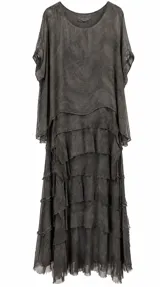 Vestido largo gris de corte fluido, con diseño de múltiples capas y volados con bordes rústicos, escote redondo y mangas cortas amplias.