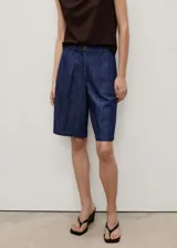 Short de denim azul con tiro medio, trabillas, cierre frontal con cremallera y botón, pinzas delanteras y bolsillos laterales.