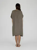 Vestido midi de lino color beige, con cuello en V, cierre frontal parcial con botones y mangas cortas con dobladillo.