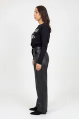 Pantalón de corte recto confeccionado en cuero sintético negro, con cierre frontal, botón y bolsillos laterales.