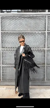 Bolso bandolera negro de cuero gamuzado con flecos largos. Tiene cierre superior y dos bolsillos frontales con cierre.