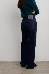 Pantalón de jean negro de corte recto y tiro medio, con cierre frontal de botón y cremallera, y bolsillos laterales y traseros.