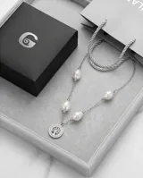 Collar de cadena de eslabones de acero con perlas barrocas intercaladas y un dije circular central con diseño de árbol de la vida y borde con incrustaciones de circonias.