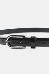 Cinturón fino de 2 cm de ancho, confeccionado en piel 100% con acabado liso. Presenta una hebilla metálica de diseño geométrico y cierre de espiga.