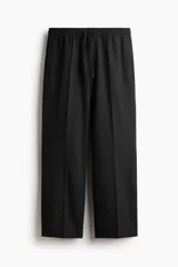 Pantalón de corte relajado y pierna recta, confeccionado en tejido suave de color negro. Presenta cintura elástica con cordón de ajuste, pliegues frontales y traseros, bolsillos laterales discretos y un bolsillo posterior insertado.