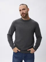 Sweater de tejido de punto fino en color gris, con cuello redondo, mangas largas y puños acanalados. Presenta un diseño liso con un pequeño detalle bordado en el pecho.