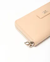 Billetera Edita de símil cuero color beige, con cierre perimetral y aplique metálico frontal con las iniciales XL.