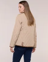 Campera matelaseada Michael Kors, de color beige con ribetes de ecocuero marrón. Cuenta con cuello con solapa, cierre frontal con broches metálicos, bolsillos laterales con cierre y mangas largas.