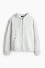 Campera con capucha de felpa gris melange, con cierre frontal, bolsillos tipo canguro y cordón ajustable. Presenta hombros caídos, corte holgado y puños y bajo en punto acanalado.