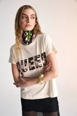 Remera color crema con estampado de la palabra "Queen" en letras negras con contorno rosa. Cuello redondo y corte holgado.