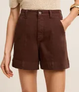 Short regular de talle alto confeccionado en sarga de color marrón, con trabillas para cinturón, cierre con botón y cremallera, bolsillos delanteros y traseros, y pespuntes en contraste.
