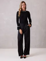 Pantalón palazzo de satén color negro, de tiro alto con pretina delantera estructurada, pasadores para cinturón y bolsillos laterales. Presenta una caída fluida y amplia, con elástico en la parte posterior de la cintura para mayor ajuste.