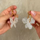 Caravanas con diseño de flor de tres pétalos en resina blanca con efecto marmolado, unidas a un aro metálico dorado.