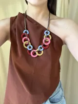 Collar con aros de acrílico entrelazados con tiento sintético color chocolate. Tiene nudo ajustable para regular el largo.
