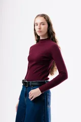 Camiseta de ajuste entallado, color bordó, con cuello alto y mangas largas.