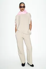 Pantalón de tiro medio confeccionado en tejido de punto elástico con pierna recta. Cuenta con cintura elástica ajustable mediante cordones y bolsillos laterales.