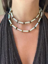 Collar doble de estilo choker/corto, compuesto por bastones cilíndricos de vidrio blanco nacarado intercalados con piedras naturales facetadas de ojo de tigre.