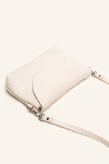 Cartera bandolera color beige, confeccionada en 100% cuero, con solapa redondeada, detalle de flor grabada y correa larga ajustable.