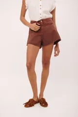 Short de jean color marrón óxido con costuras en rojo, tiro alto y ruedo deshilachado.