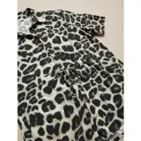 Conjunto de dos piezas compuesto por una camisa de manga corta con cuello italiano y cierre frontal de botones, y un short con cintura elástica y bolsillos laterales. Ambas prendas presentan un diseño estampado de animal print.