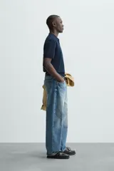 Jersey de punto color verde oliva, de calce relajado (relaxed fit), con cuello solapa y abertura frontal en forma de V. Es de manga corta y presenta acabados en rib en puños y ruedo.