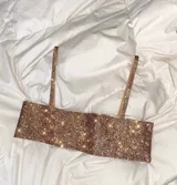 Top dorado con lentejuelas, breteles finos y espalda descubierta con cierre de cadenita.