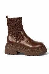 Botas de caña media con diseño tipo calcetín en tejido acanalado color marrón. Presentan una puntera redondeada y cuerpo de cuero sintético, con una suela track gruesa y dentada del mismo tono.