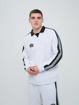 Buzo deportivo Umbro modelo Mixtape, color negro con cuello polo blanco y franjas blancas en las mangas con logo de la marca. Cuenta con puños y cintura elastizados.
