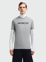 Remera gris de algodón con cuello redondo y manga corta. Presenta el logo de la marca Moncler estampado en el pecho.