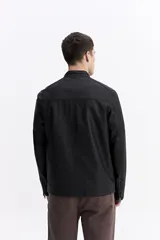 Campera de cuero sintético color negro, con cuello mao, cierre frontal y bolsillos laterales con cierre. Presenta detalles de costuras acolchadas en los hombros y un bolsillo pequeño con cierre en el pecho.