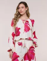 Conjunto de dos piezas de crep compuesto por una blusa holgada con escote en V y mangas largas abullonadas, y un pantalón palazzo tiro alto con pretina elástica. Presenta un estampado floral en tonos rosados sobre base blanca.