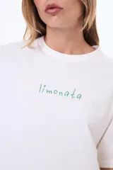 Remera de algodón color blanco, de corte holgado y manga corta, con estampado gráfico en la espalda que incluye dibujos de limones, una jarra, un vaso y un lazo.