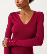 Blusa de punto de corte alargado, color negro, con escote redondo, manga larga y detalle de botones decorativos en los puños.