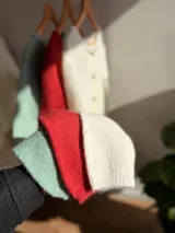 Saco tejido de punto liviano, color verde menta, con cuello redondo, cierre frontal de botones oscuros y diseño de corte corto.