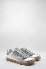 Zapatillas bajas de cuero color crema con detalles en marrón y cordones blancos.