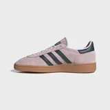 Championes Adidas modelo Handball Spezial, confeccionados en gamuza color rosado con las icónicas tres tiras y detalle en el talón en color azul oscuro. Presentan puntera en forma de T y suela de caucho color caramelo.
