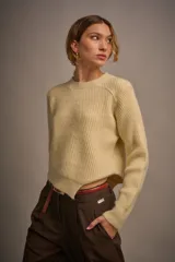 Sweater de punto color crudo con cuello redondo y corte asimétrico en el bajo.