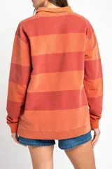 Sweater tipo polo de algodón peinado con diseño de rayas horizontales en tonos rojizos y terracota, cuello camisero y mangas largas con puños.