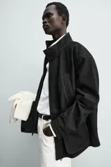 Parka de cuero color negro, de corte relajado, con cuello alto, cierre frontal con cremallera oculta y solapa con botones a presión. Cuenta con bolsillos frontales tipo cargo con solapa en la cadera y bolsillos de vivo en el pecho.